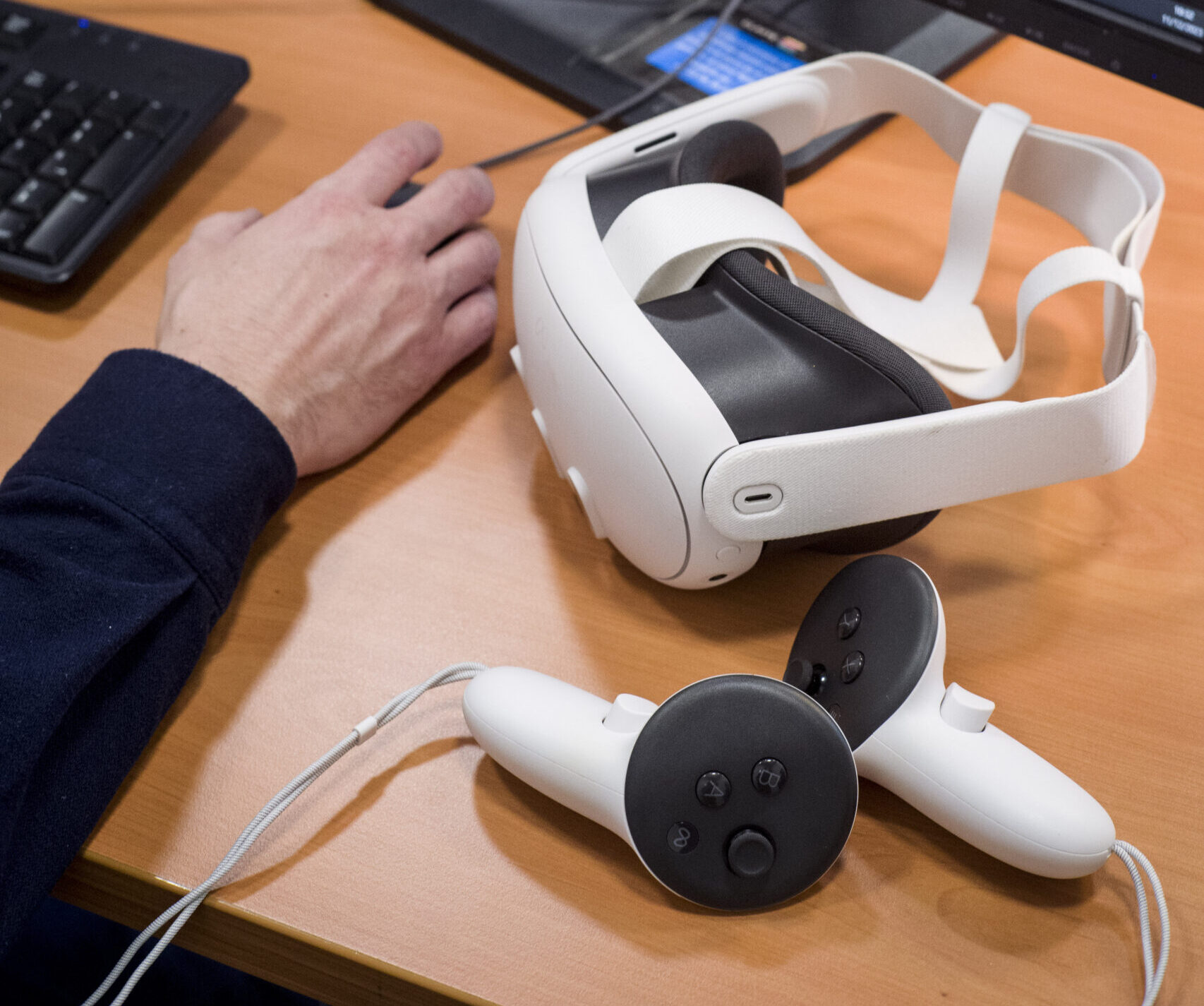 Sur une table, un casque de réalité virtuelle et deux manettes